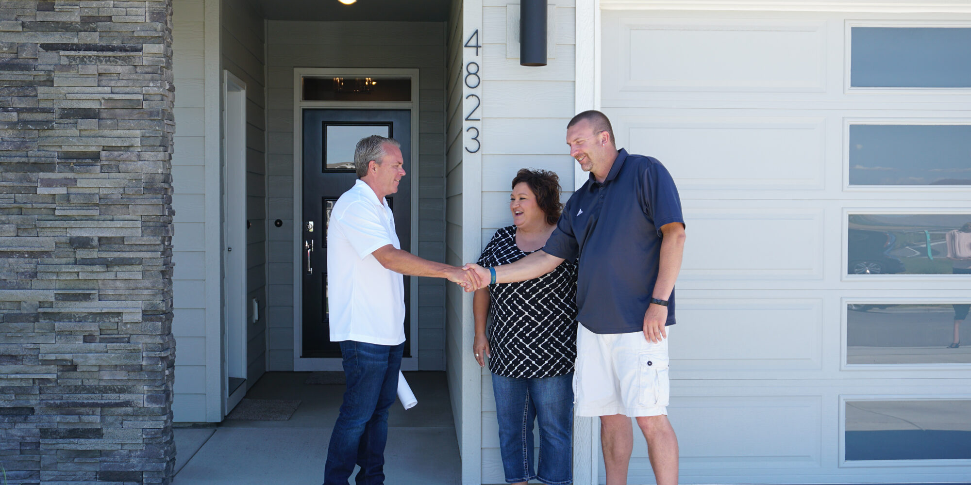 Bruce Tanninen shaking hands with satisfied home owners